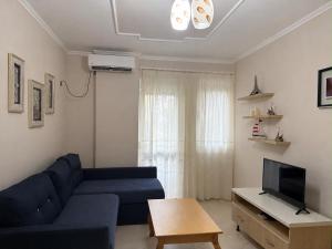 a living room with a blue couch and a tv at Daniels apartment in Shëngjin