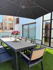 a wooden table with chairs and an umbrella at Casa Tramuntana in El Port de la Selva