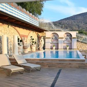 a swimming pool with two chairs and a fountain at Villa Eidos b&b in Domicella