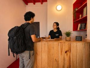 a man with a backpack talking to a woman at a counter at Hope Hostels, Fort Kochi in Fort Kochi