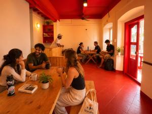 a group of people sitting at a table in a room at Hope Hostels, Fort Kochi in Fort Kochi