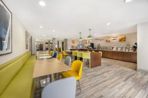 a restaurant with yellow chairs and tables and a counter at Comfort Suites Albuquerque-North Journal Center in Albuquerque