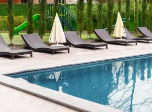 a row of lounge chairs next to a swimming pool at next green in Makhinjauri