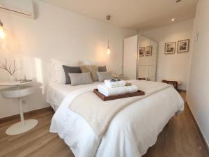a white bedroom with a large white bed and a sink at Casa da Mouraria in Faro