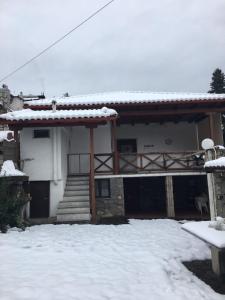a house with snow on the ground in front of it at Ξενώνας Το Πάλαι Ποτέ in Polydrossos