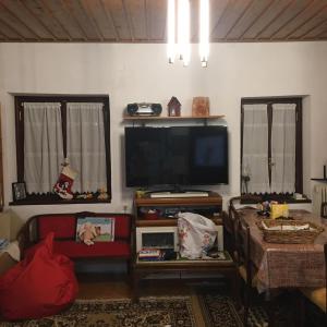 a living room with a flat screen tv and two windows at Ξενώνας Το Πάλαι Ποτέ in Polydrossos
