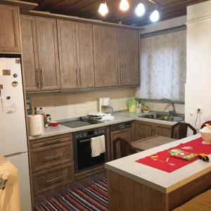 a kitchen with wooden cabinets and a white refrigerator at Ξενώνας Το Πάλαι Ποτέ in Polydrossos