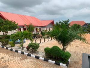 a building with a red roof with palm trees in front of it at ffa resort centre in Akure