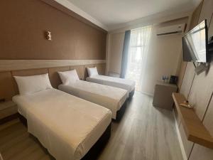 a hotel room with two beds and a flat screen tv at Fortuna Hotel in Batumi