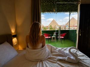 a woman sitting on a bed looking out a window at Master kings of the pyramids and Sphinx in Cairo