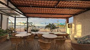 a patio with tables and chairs and a view of the beach at Solar Itacaré - Charme e aconchego. in Itacaré