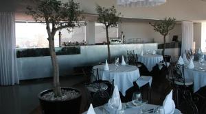 a dining room with white tables and chairs with trees at Hotel Dighton in Oliveira de Azemeis
