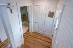 a hallway with a white door and wooden floors at Magnolia Honeymoon Cottage in Santa Rosa Beach