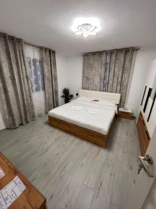a bedroom with a large bed and wooden floors at Căsuța Găvruj in Săcel