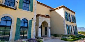 Chateau Del Valle في إنسينادا: منزل ذو نوافذ خضراء ذات مصاريع وأزهار