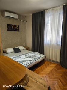 a bedroom with a bed and a table and a window at Niški kutak in Niš