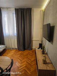 a living room with a television and a wooden table at Niški kutak in Niš