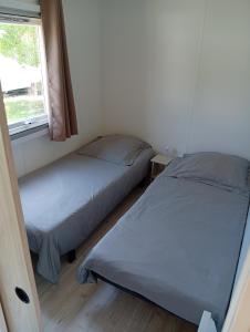two beds in a small room with a window at FH Mobile home Camping des Viviers in Lège-Cap-Ferret