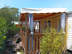 a small house with a porch with a canopy at FH Mobile home Camping des Viviers in Lège-Cap-Ferret