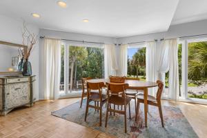 a dining room with a table and chairs and windows at 735 Spinnaker Beach House in Seabrook Island