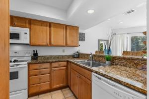 a kitchen with wooden cabinets and a sink at 735 Spinnaker Beach House in Seabrook Island +25 photos