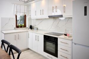 a white kitchen with white cabinets and a black oven at Casa di Fava in Agios Nikolaos