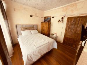 a bedroom with a white bed and a wooden floor at Fazilet Hanım Konağı in Şahinbey