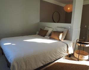 a bedroom with a large white bed with brown pillows at APPART en THÈSE Appartement climatisé Accessible PMR Proche Dijon et CEA Valduc in Moloy