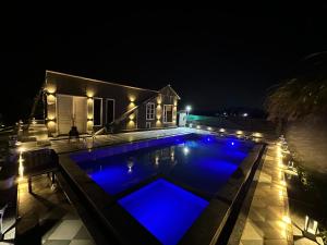 a swimming pool at night with blue lights at Sukoon Farms in Greater Noida