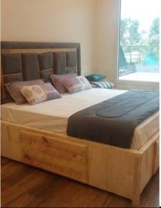 a large wooden bed in a room with a window at Sukoon Farms in Greater Noida