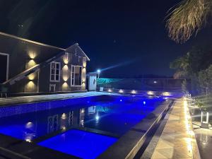 a swimming pool in front of a house at night at Sukoon Farms in Greater Noida +13 photos