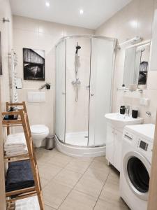 a bathroom with a shower and a washing machine at Kairos Apartments - Lothus - darmowy garaż podziemny, ścisłe centrum in Gliwice