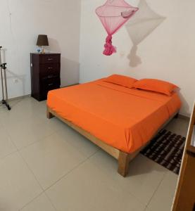 a bedroom with a bed with an orange comforter at ponta gato residence in Tarrafal