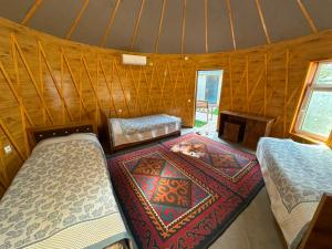 a room with two beds and a rug in a yurt at Датка in Arslanbob
