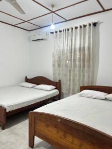 a bedroom with two beds and a window at Lion Isle Residence in Anuradhapura