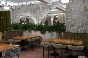 a restaurant with wooden tables and chairs and a stone wall at Zielona Przystań - Noclegi in Maków Podhalański