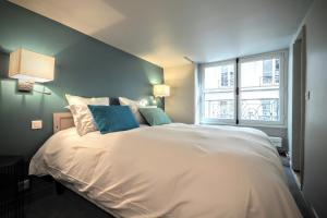 1 dormitorio con 1 cama blanca grande y ventana en Richelieu ChicSuites, en París