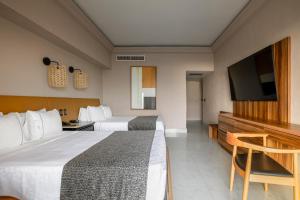 a hotel room with two beds and a flat screen tv at Royal Villas Resort in Mazatlán
