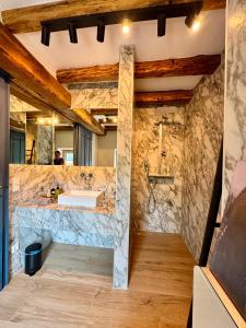 a bathroom with a stone wall with a shower and a sink at Casa Di Pietra in Maria Saal +50 photos
