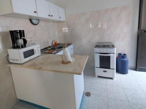 a kitchen with a counter with a microwave and a stove at Ponta Gato Residence in Tarrafal