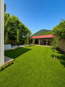 a yard with a building with a green lawn at Hillside villa in Gabala