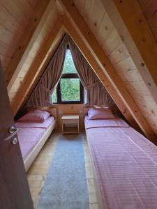 two beds in a attic room with a window at Vila Milena in Žabljak