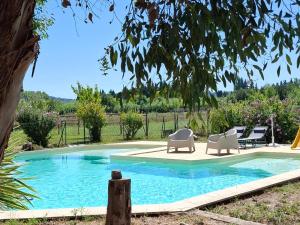 a swimming pool with two chairs and a table at Chambre des Alpilles in Eygalières
