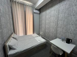 a small bedroom with a bed and a table at Shodlik Hotel 