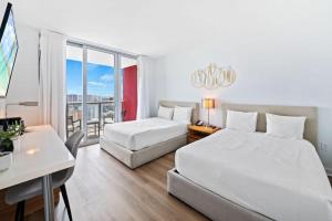 a hotel room with two beds and a table and a desk at Upper Studio Stunning Intracoastal Views in Hallandale Beach