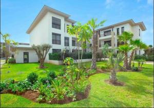 a large house with palm trees in a yard at Joli appartement à Tamaris in Dar Bouazza