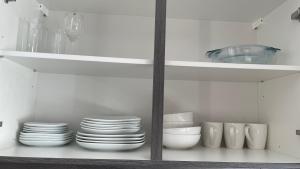 a white kitchen with plates and bowls on shelves at Ferienwohnung Bayer in Gründau +8 photos