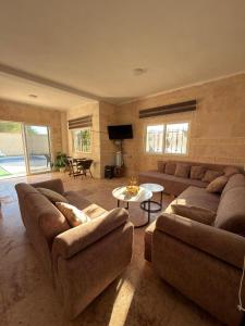 a living room with two couches and a table at Entire Home Near Deadsea & Baptism Site Pool, Garden, BBQ, Great Price in Shūnat Nimrīn