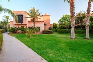 a house with palm trees and a sidewalk at Atlas Golf Resort in Marrakesh