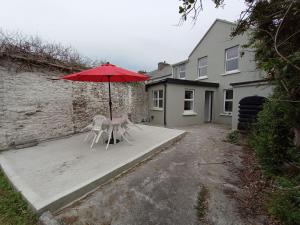 a table and chairs under an umbrella in a driveway at Mutton House in Milltown Malbay